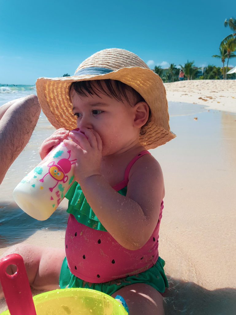 Baby on beach drinking milk