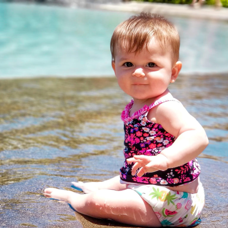 baby on edge of pool smiling