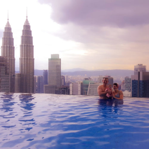 family travel with baby. family in pool in front of kuala lumpur skyline