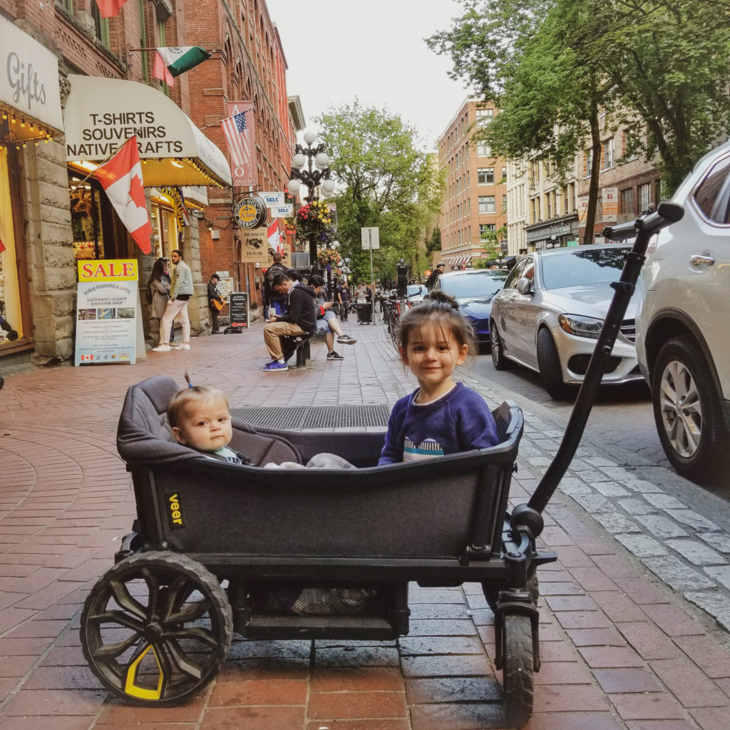 Toddler and baby in veer wagon on city street