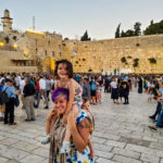 Woman holding toddler and baby in front of western wall in jerusalem