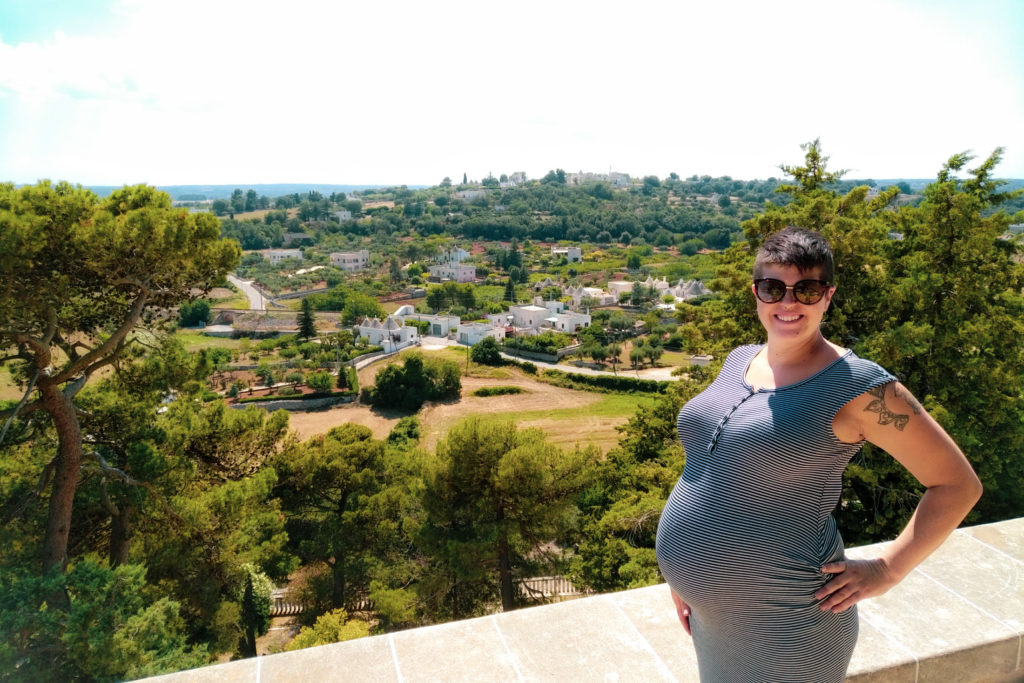 pregnant woman overlooking green landscape dotted with white trulli