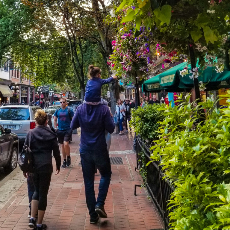 toddler on father's shoulders reaching for flowers in vancouver