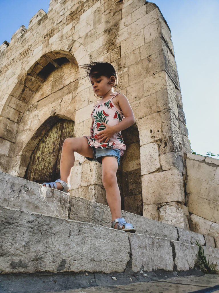toddler in jerusalem standing in front of ancient gate