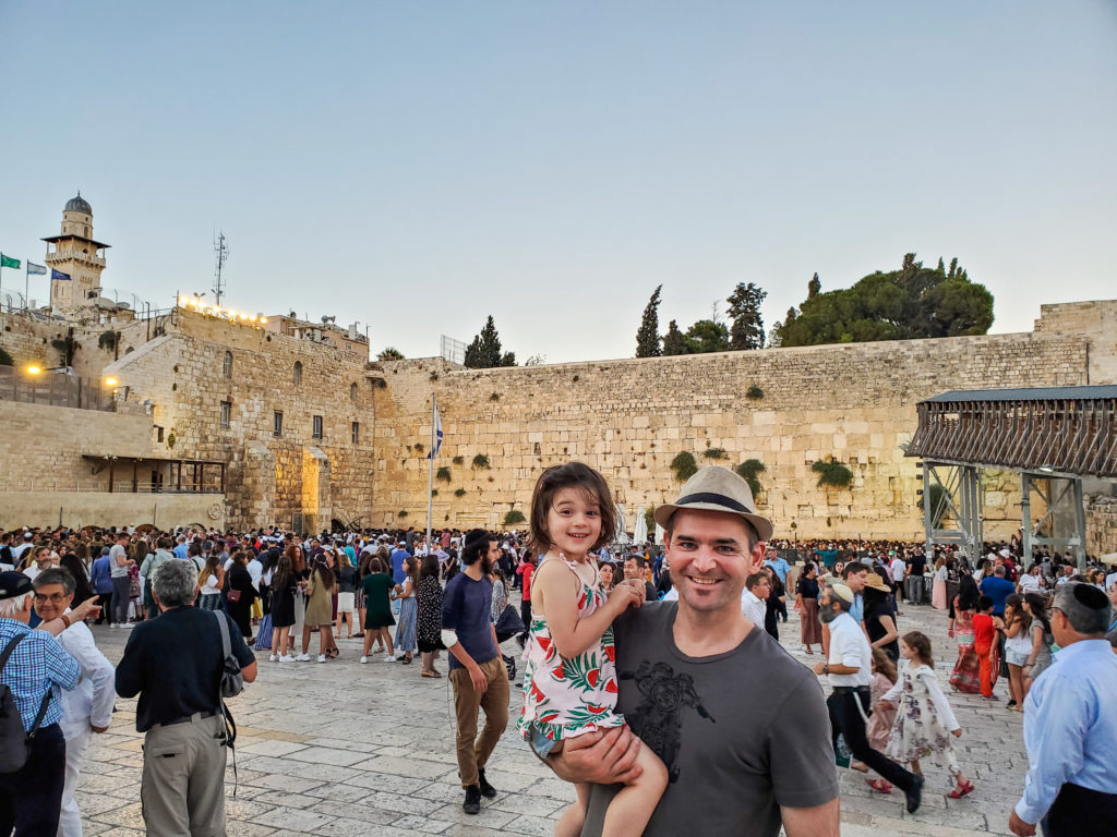 father and toddler at western wall with crowd behind them