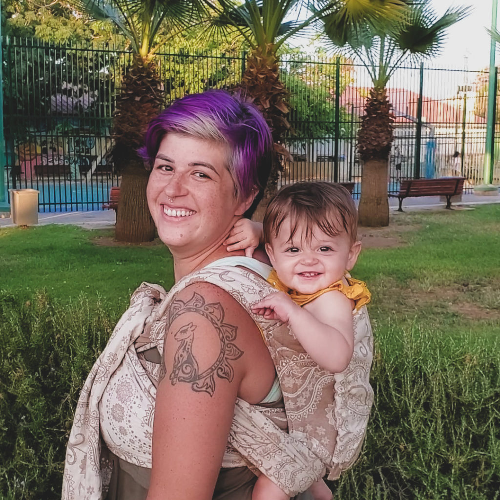 woman wearing baby in baby carrier both smiling