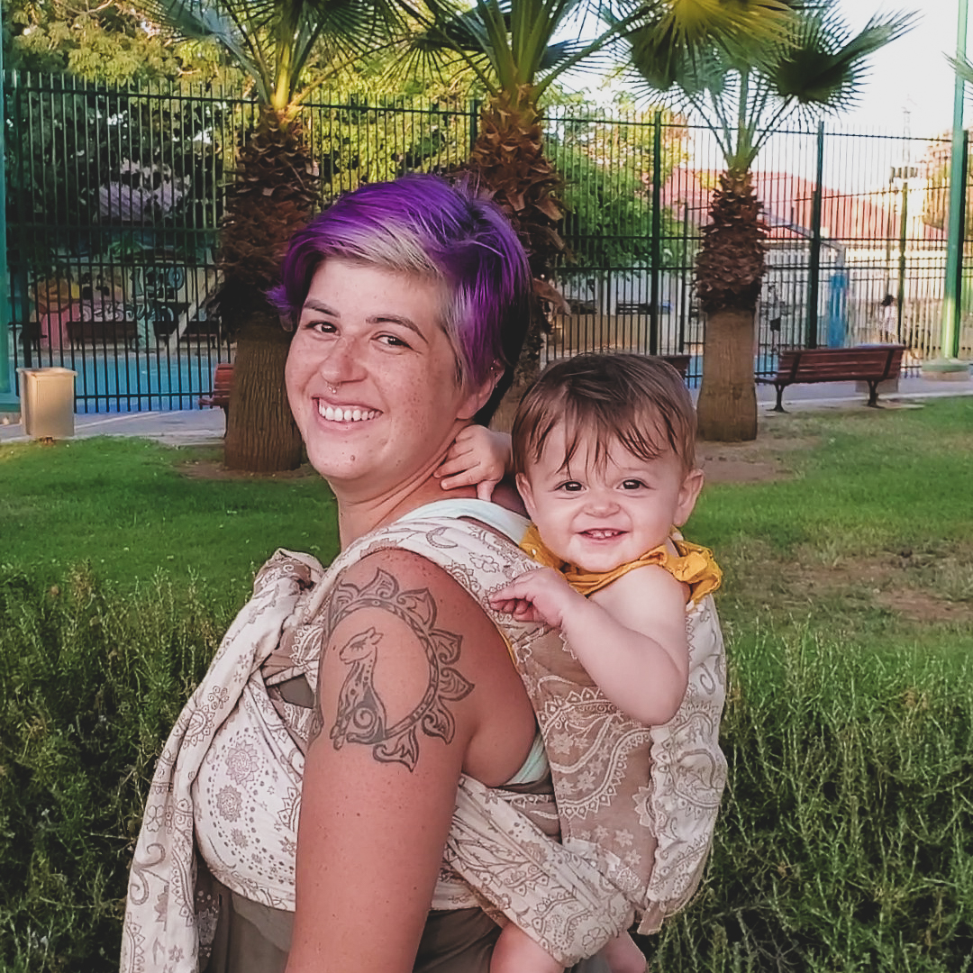 woman wearing baby in baby carrier both smiling