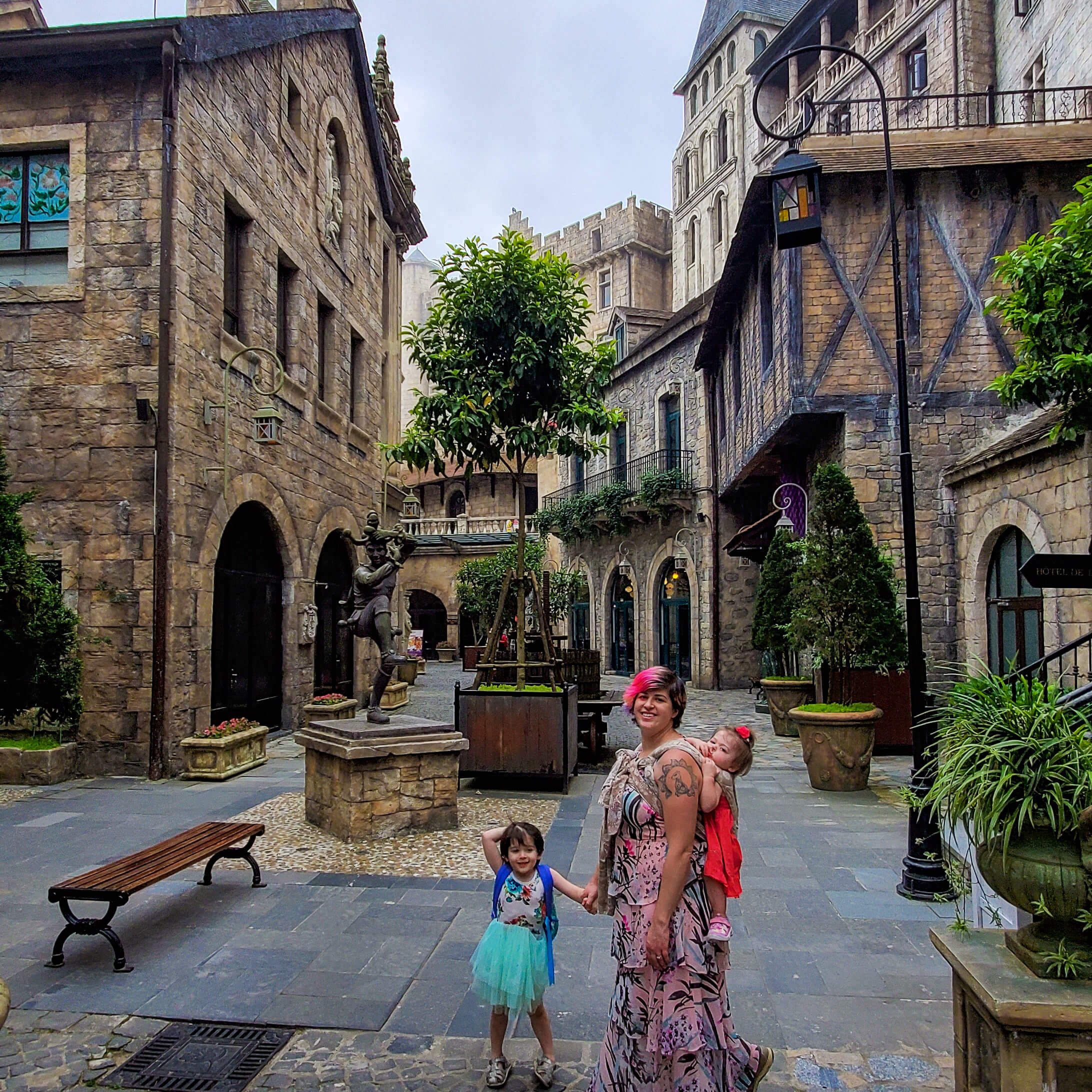 woman wearing baby and holding toddler's hand in medieval village