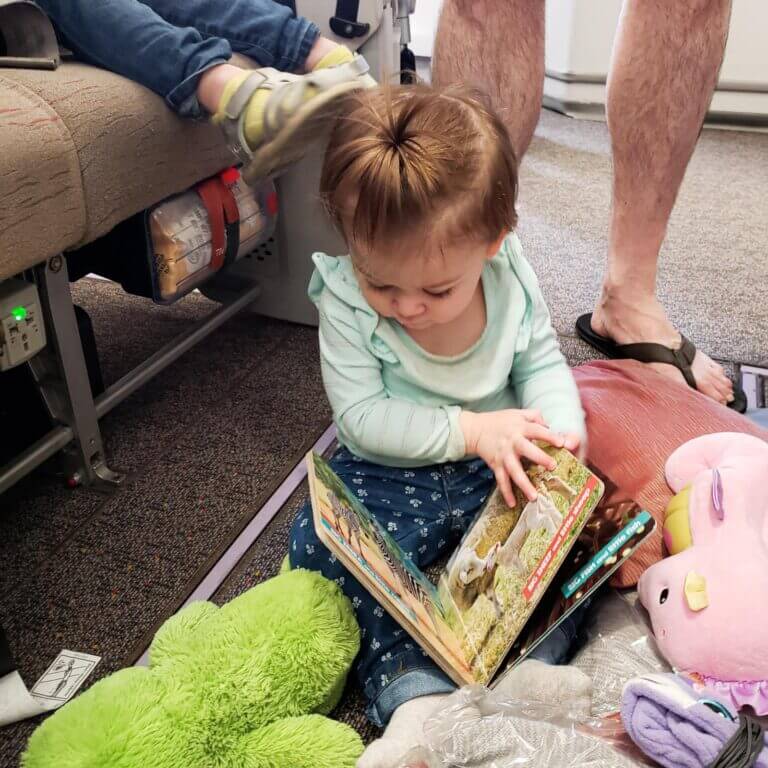 baby on airplane floor looking at books