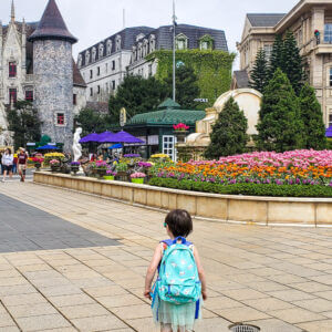 toddler wearing backpack standing walking toward gothic style town