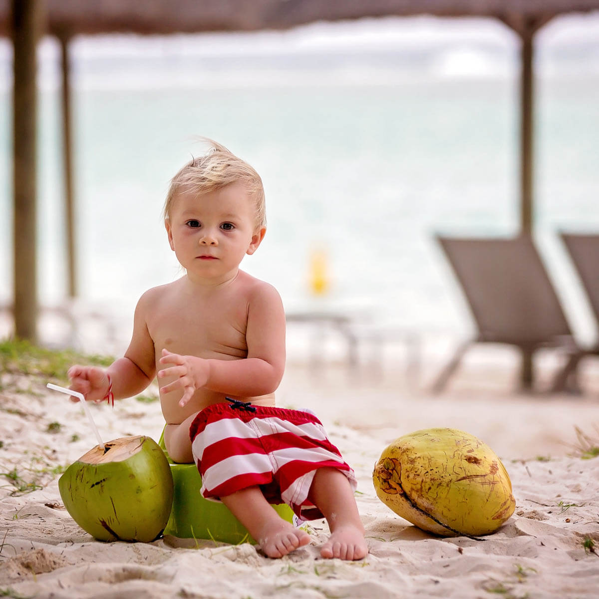 Little toddler boy, learning potty training on the beach on a tropical island