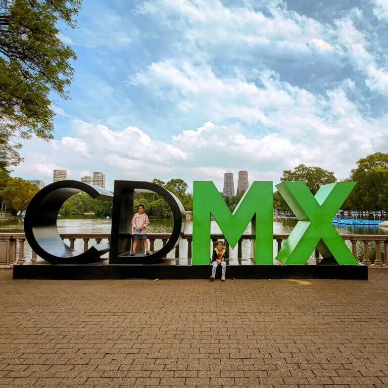 large CDMX sign with lake and skyline in backgroudn and toddler and child on the letters