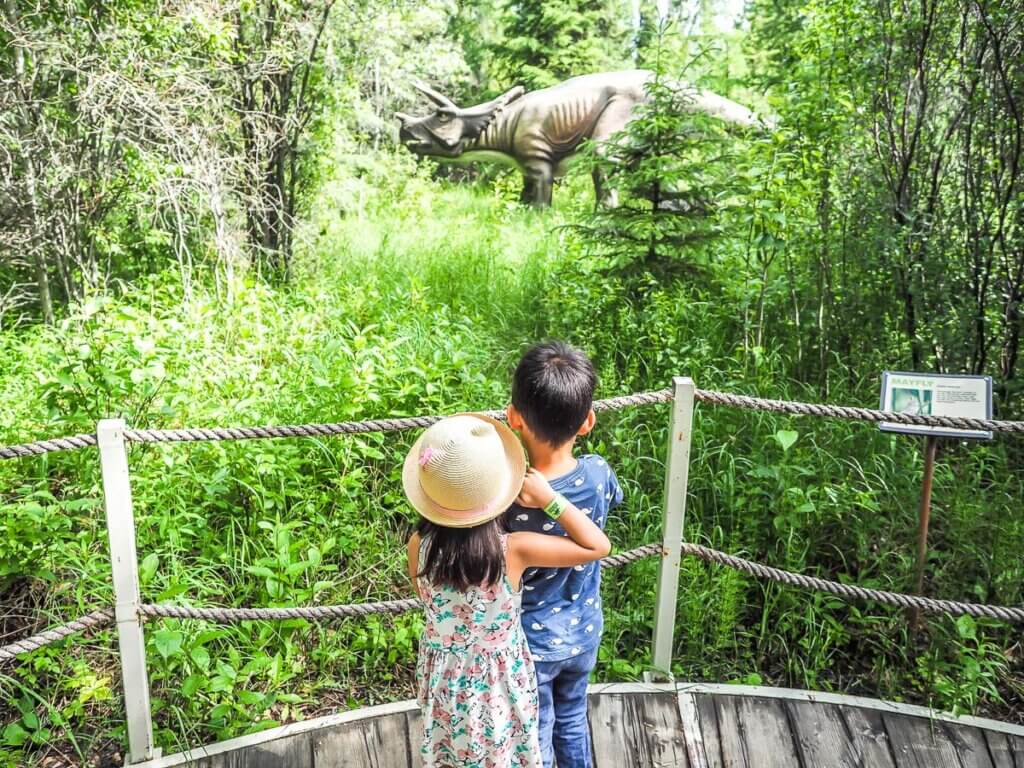 edmonton toddlers looking out at large dinosaur sculpture