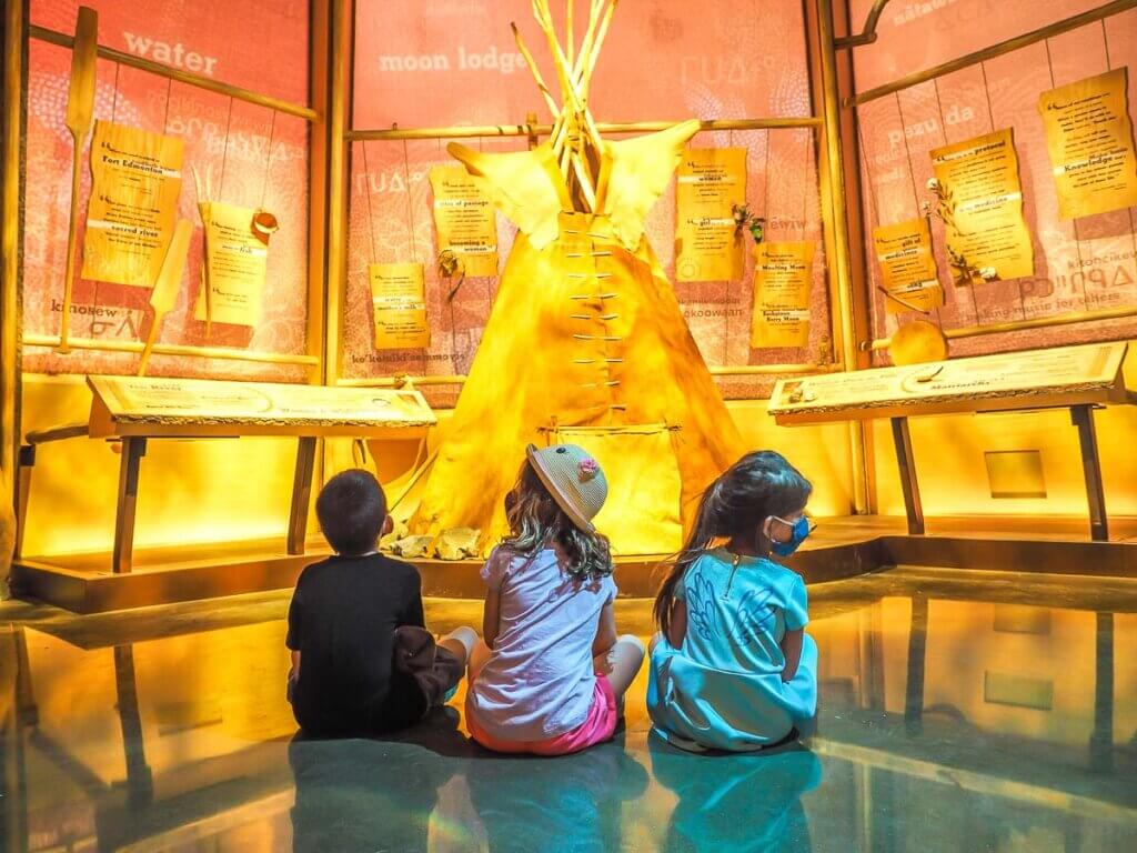 three children in a museum looking at indigenous artifacts