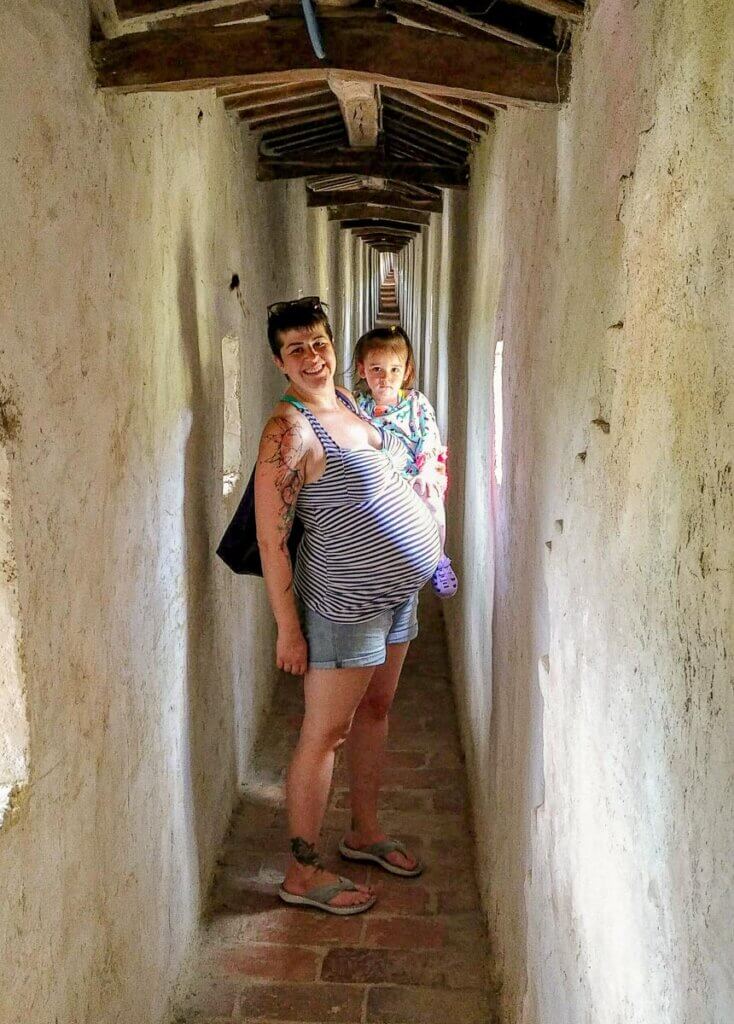 pregnant woman holding a baby in a stone castle tunnel